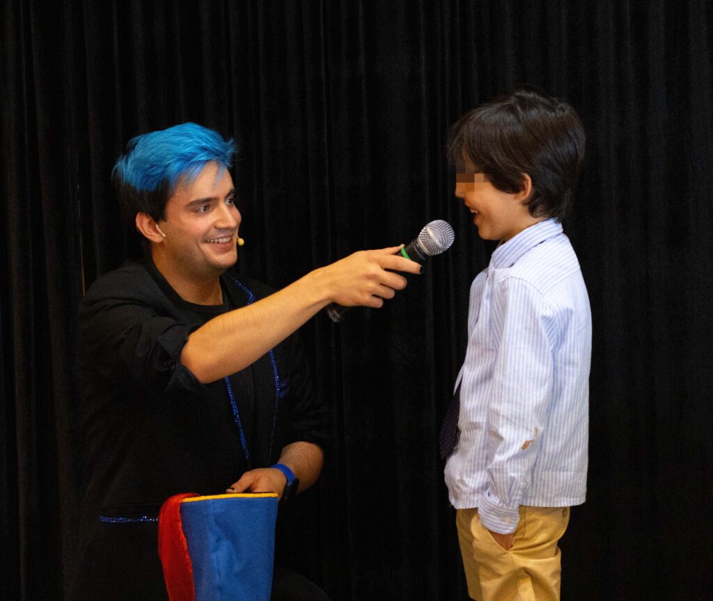El mago Ivan Torres en una comunión con un micrófono hablando con un niño.