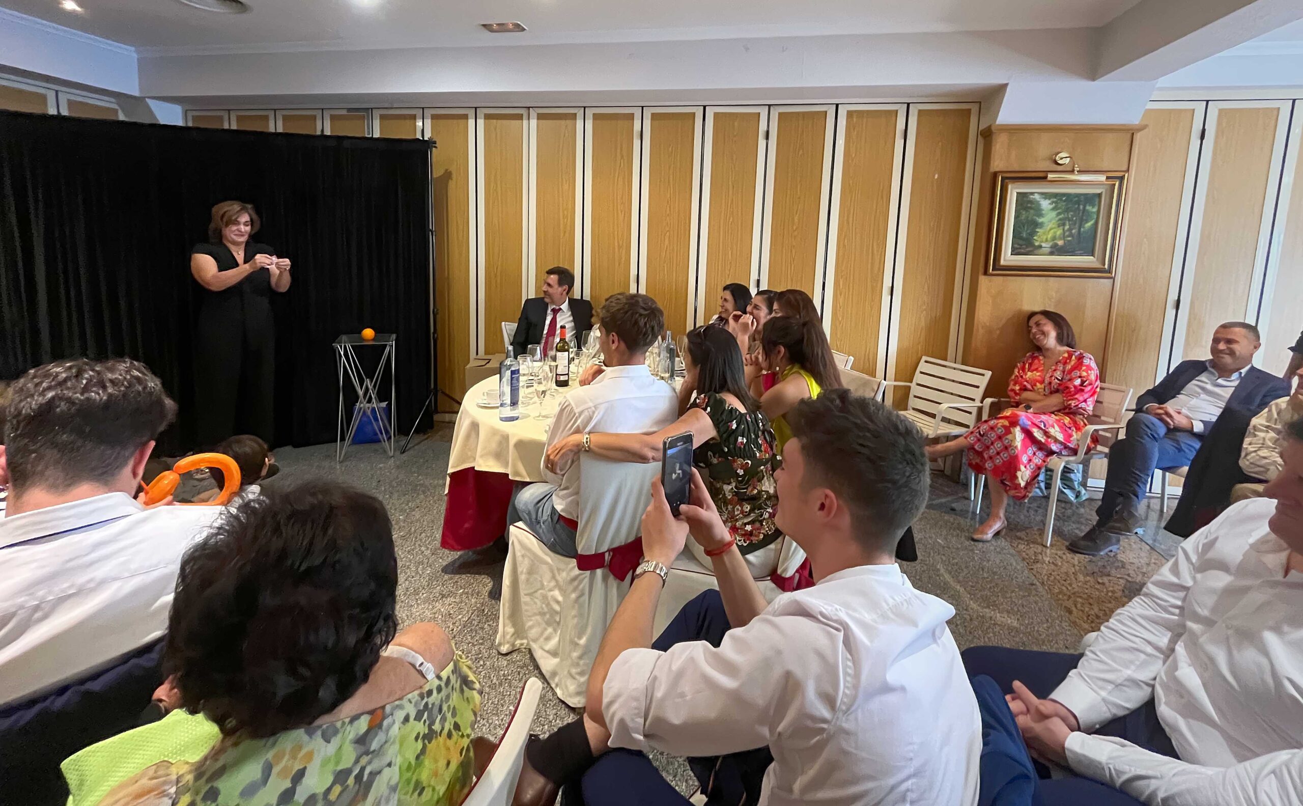 Momento del show de uno de los magos para comuniones de Espectáculos IluminARTE donde hay una mujer en el escenario y el público alrededor riéndose
